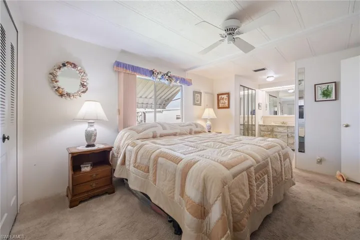 Carpeted bedroom with a closet, a ceiling fan, connected bathroom, and wooden walls