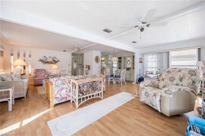 Living room featuring a ceiling fan, light wood-style floors, and a chandelier