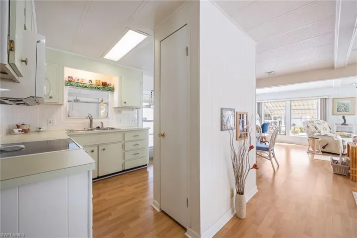 Kitchen with light wood-type flooring, decorative backsplash, light countertops, and white cabinets