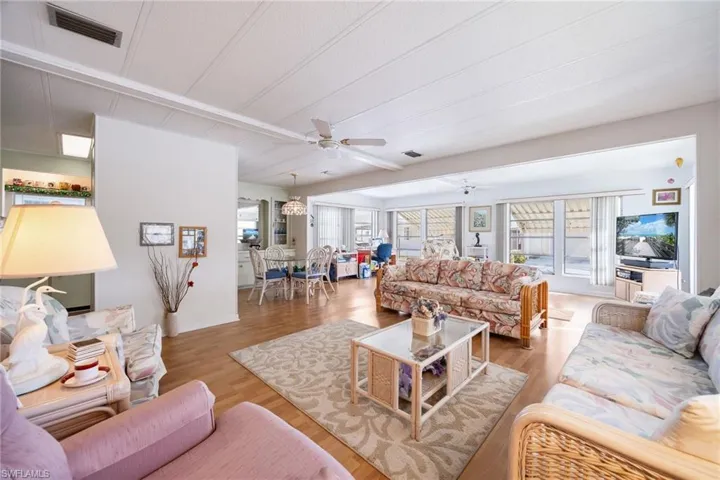 Living area featuring wood finished floors, a ceiling fan, and a chandelier