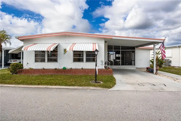Manufactured / mobile home featuring a carport, concrete driveway, and a front yard