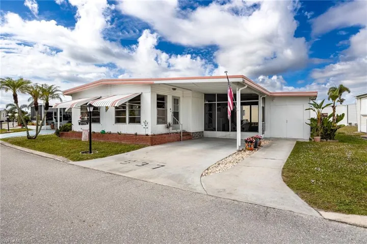 Manufactured / mobile home with a front lawn, an attached carport, and driveway