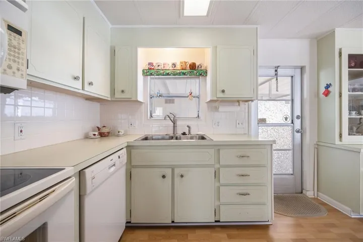 Kitchen with white appliances, decorative backsplash, plenty of natural light, and light wood-style flooring