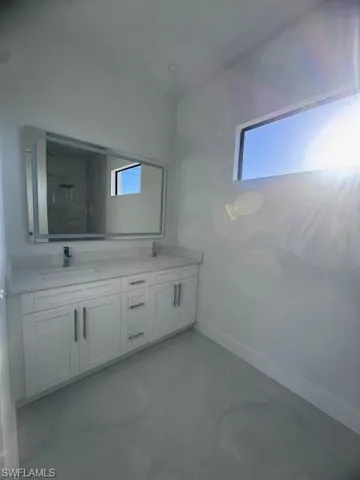 Modern bathroom featuring a dual vanity with white cabinetry and a light-toned countertop