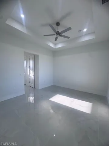 Spacious room featuring a contemporary ceiling fan, recessed lighting, and a tray ceiling