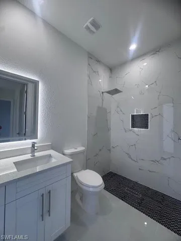 Contemporary bathroom featuring a walk-in shower with large format marble-look wall tiles and a black and white herringbone pattern tile floor