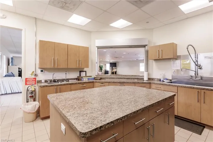 Community Clubhouse Kitchen with light tile patterned floors, a kitchen island, and a paneled ceiling