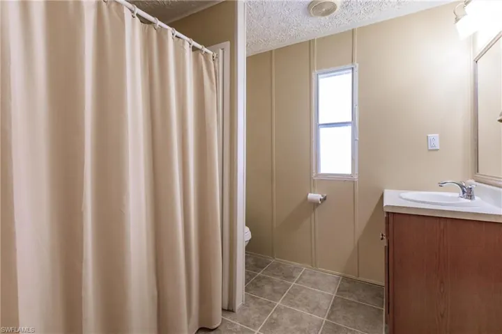 Bathroom #1 with a textured ceiling, tile patterned flooring, vanity, and toilet