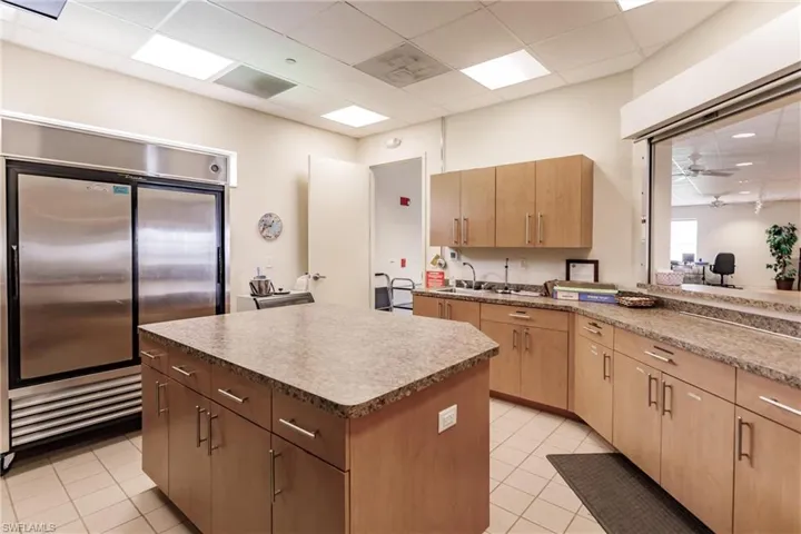 Community Kitchen with stainless steel built in refrigerator, ceiling fan, a center island, and light tile patterned floors