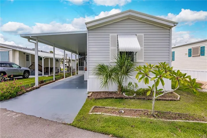 Front featuring a carport and window awningand a front yard