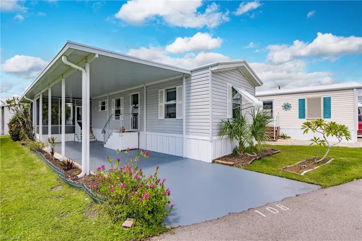 Manufactured home featuring a carport and a front lawn