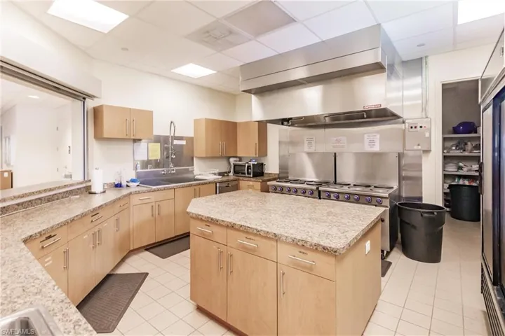 Community Kitchen featuring light stone counters, light brown cabinetry, light tile patterned flooring, and a paneled ceiling