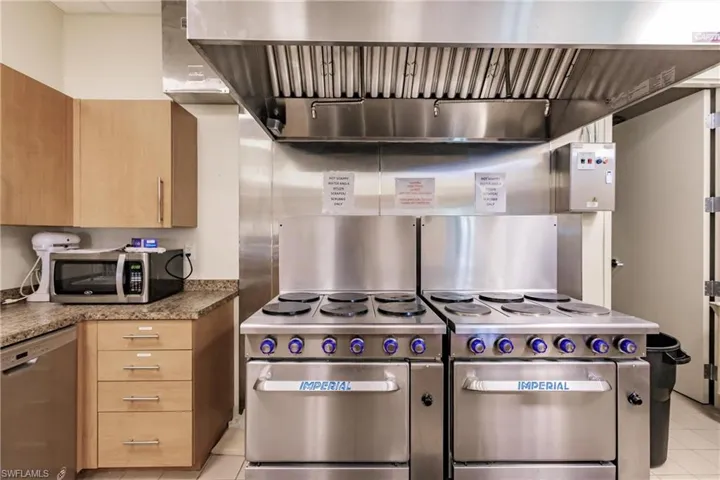 Community Clubhouse Kitchen featuring appliances with stainless steel finishes, light brown cabinetry, light stone countertops, and light tile patterned floors