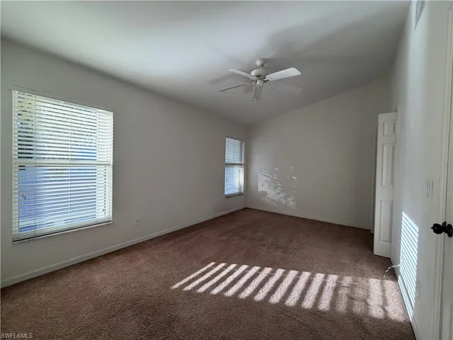 Carpeted spare room with ceiling fan and lofted ceiling