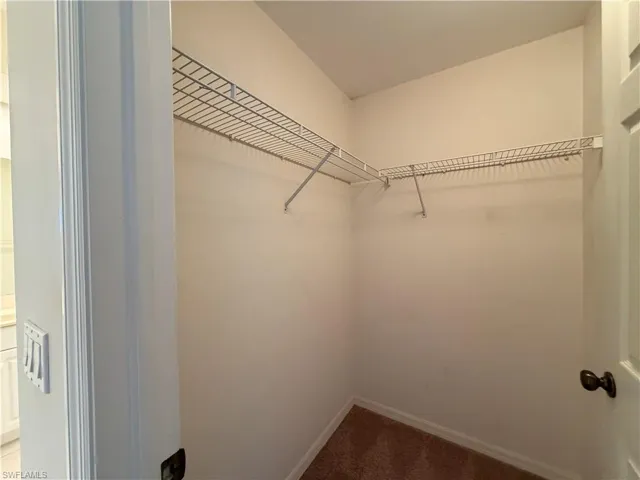 Walk in closet featuring dark carpet