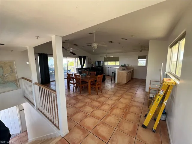 Tiled dining room featuring ceiling fan and vaulted ceiling
