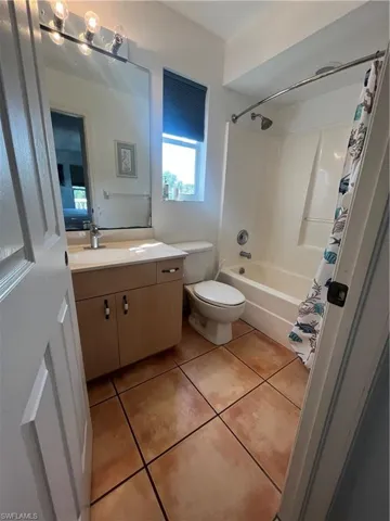 Full bathroom with tile flooring, toilet, vanity, and shower / bath combo