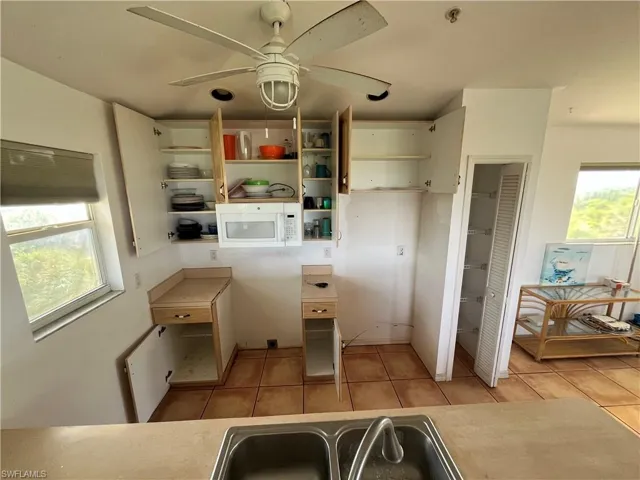 Kitchen featuring a wealth of natural light, white cabinets, ceiling fan, and light tile floors