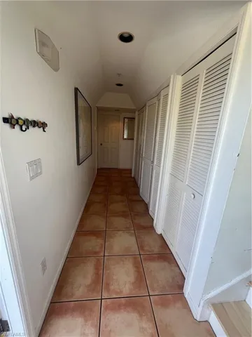 Hallway featuring vaulted ceiling and tile flooring
