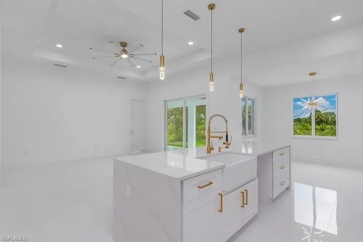 Kitchen with a center island with sink, sink, light tile flooring, and a raised ceiling
