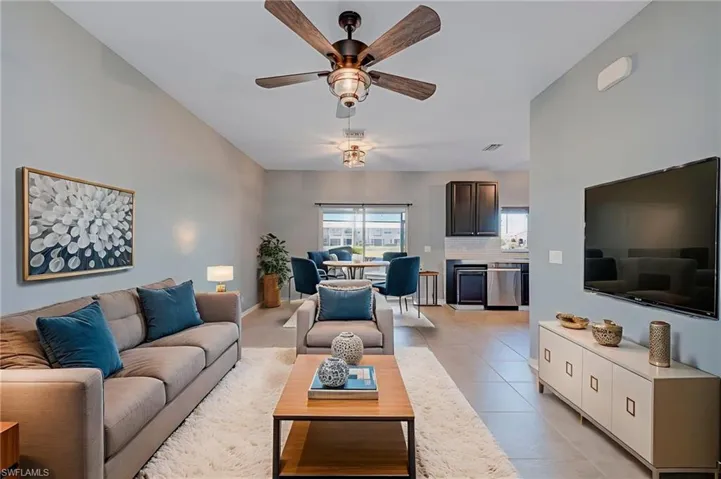 Living room featuring a ceiling fan, light tile patterned floors, and lofted ceiling