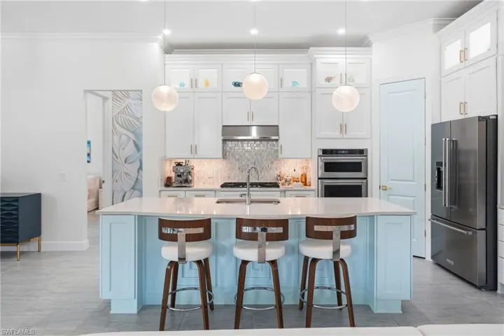 Light-filled kitchen designed for both style and function, featuring freshly painted cabinetry, an updated island with bar seating, and contemporary lighting. The open design creates a natural hub for entertaining while maintaining a sleek, move-in-ready feel.
