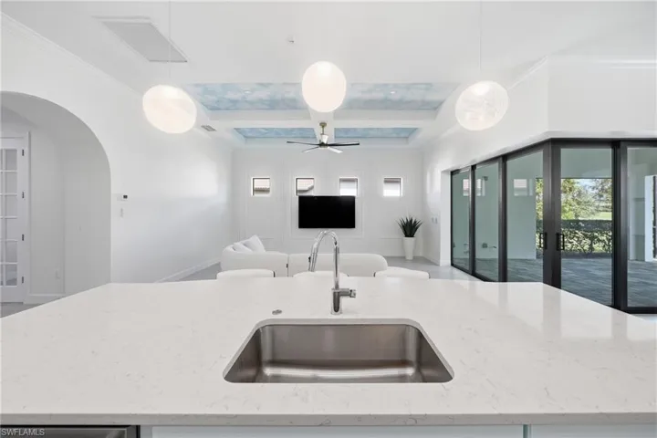 Light-filled kitchen designed for both style and function, featuring freshly painted cabinetry, an updated island with bar seating, and contemporary lighting. The open design creates a natural hub for entertaining while maintaining a sleek, move-in-ready feel.