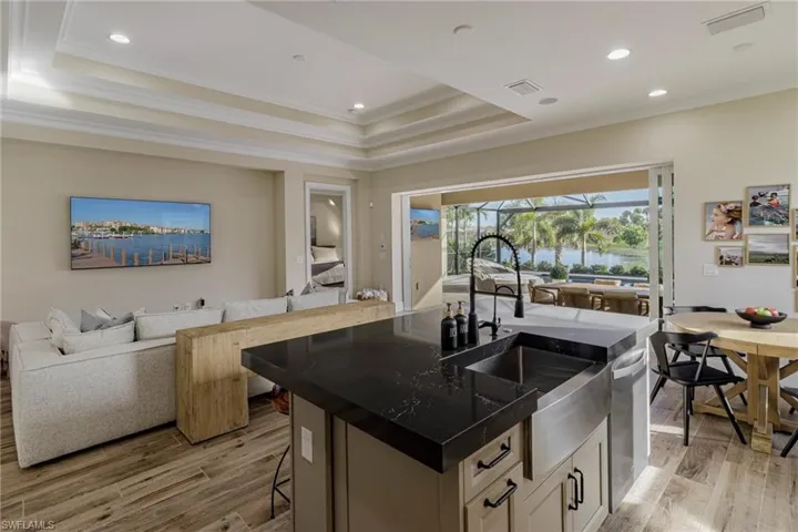 Kitchen with white cabinets, a breakfast bar, light hardwood / wood-style flooring, and a center island with sink