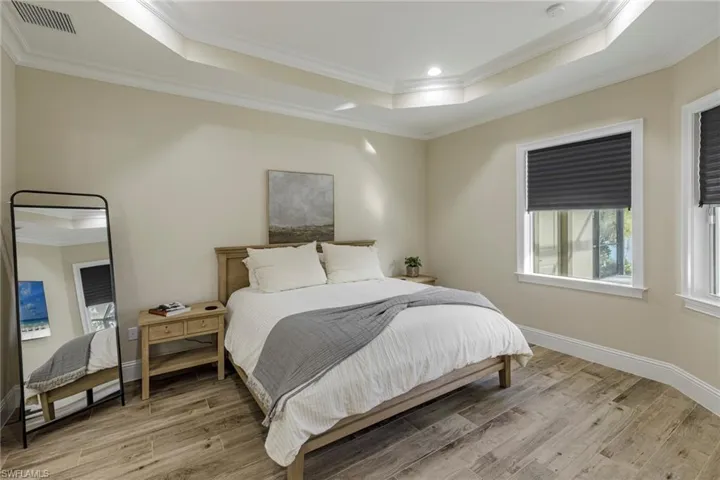 Bedroom featuring crown molding, a tray ceiling, and light hardwood / wood-style floors