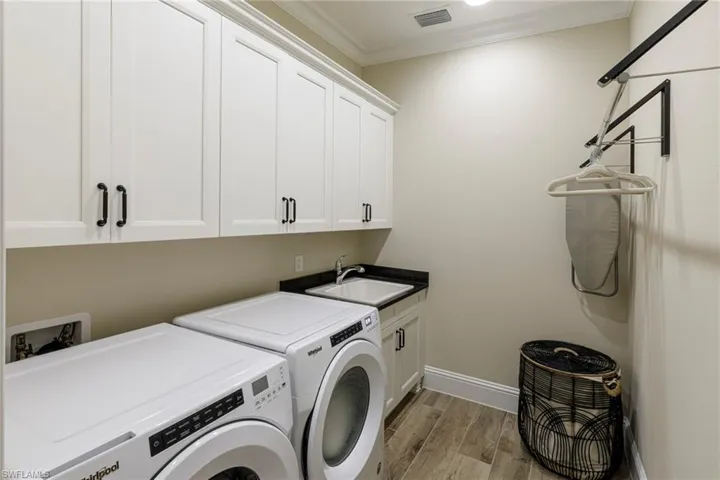 Washroom with sink, cabinets, light hardwood / wood-style floors, crown molding, and separate washer and dryer