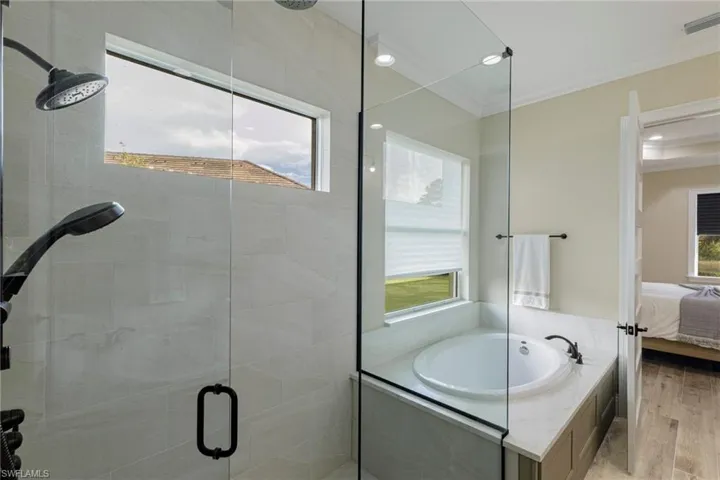 Bathroom with hardwood / wood-style flooring, shower with separate bathtub, and ornamental molding