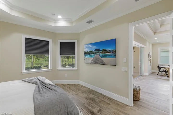 Bedroom featuring light hardwood / wood-style floors, a raised ceiling, and ornamental molding