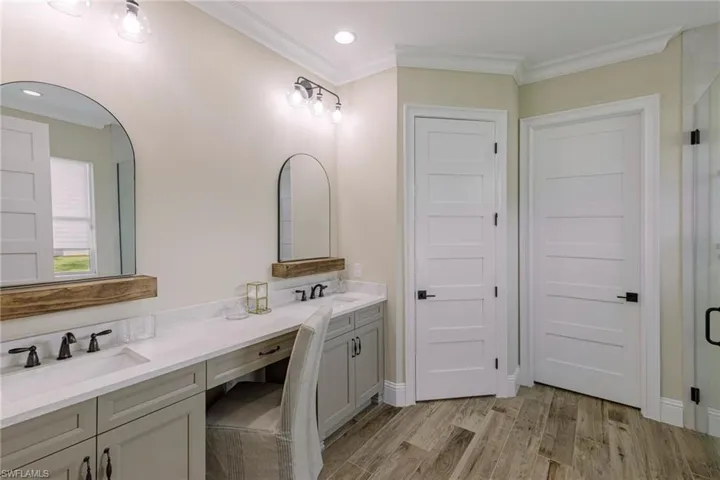 Bathroom with wood-type flooring, double sink vanity, and ornamental molding