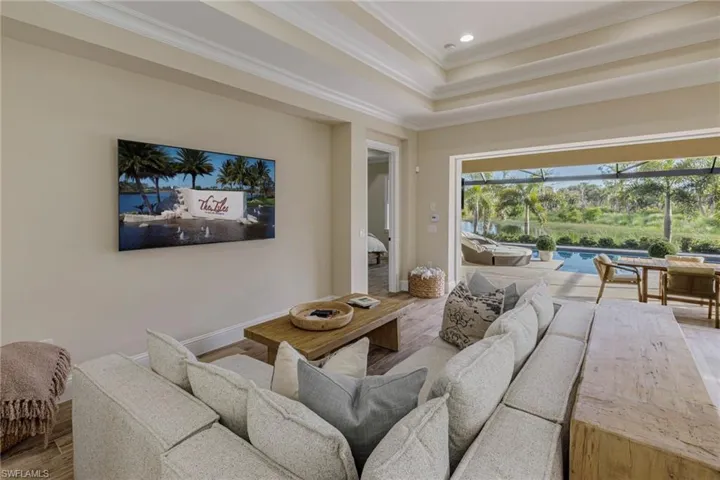 Living room with crown molding, light hardwood / wood-style flooring, and a raised ceiling