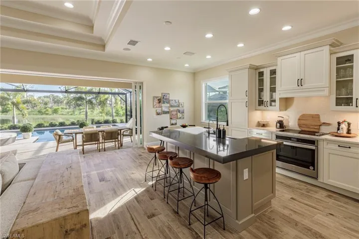 Kitchen featuring light hardwood / wood-style flooring, a kitchen island with sink, stainless steel oven, and plenty of natural light