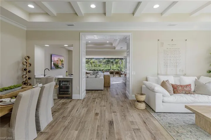 Living room with light hardwood / wood-style floors, ornamental molding, and wine cooler