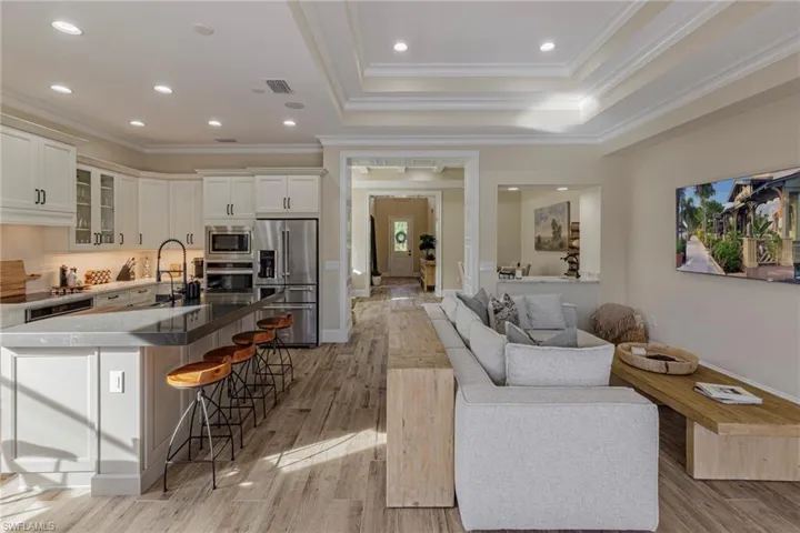Living room featuring a tray ceiling, light hardwood / wood-style flooring, sink, and ornamental molding