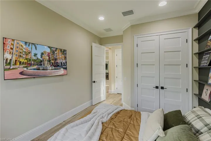 Bedroom with light hardwood / wood-style flooring, a closet, and crown molding