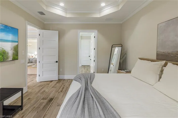 Bedroom with light hardwood / wood-style flooring, a tray ceiling, and ornamental molding