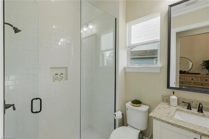 Bathroom featuring vanity, walk in shower, ornamental molding, and toilet