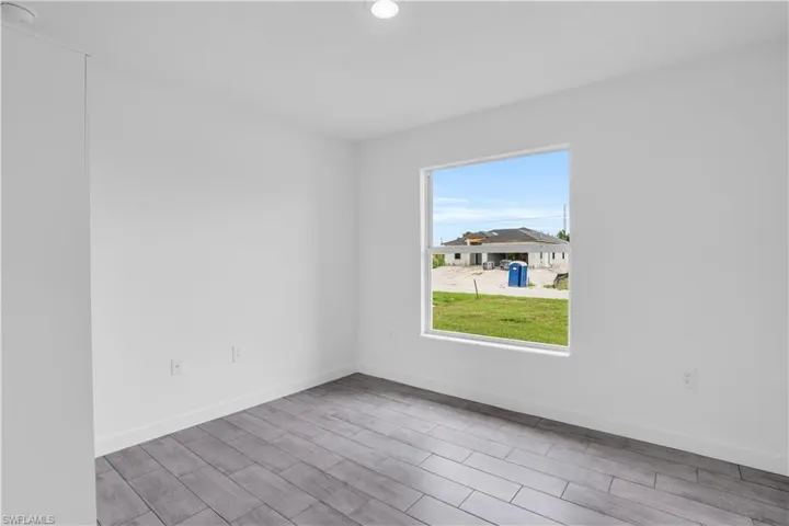 Open room with wood-finish flooring, white baseboards, and a single window