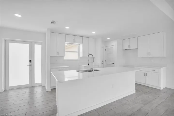 Modern kitchen featuring an expansive center island with an integrated sink and gooseneck faucet