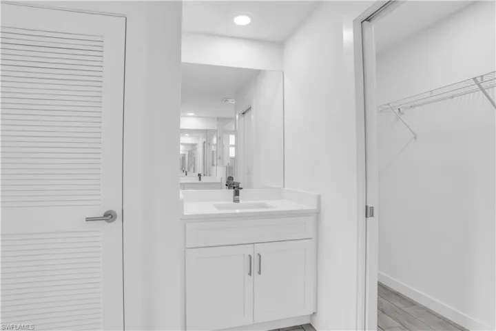 White vanity with integrated sink and chrome faucet, set beneath a large wall mirror