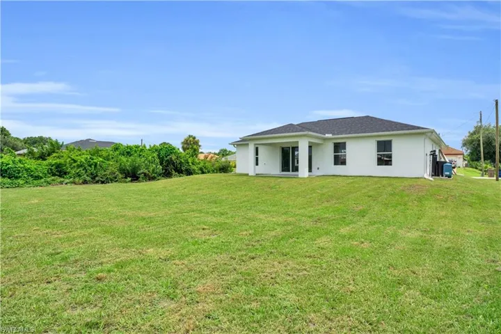 Expansive green lawn with a white stucco exterior and dark-shingle roof