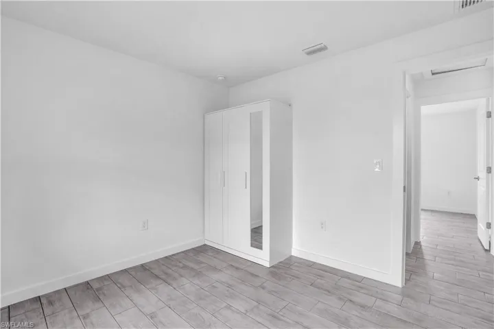 Recessed lighting illuminates wood-finish plank flooring and white walls