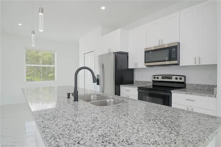 Kitchen with white cabinets, stainless steel appliances, and decorative light fixtures