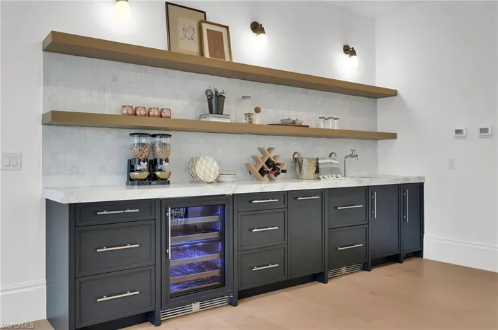 An elevated entertaining space featuring white oak cabinetry, open shelving, and Brizo fixtures, complete with a beverage fridge — perfect for serving the loft and upstairs suites