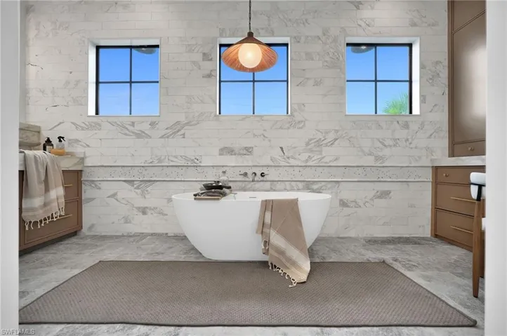 Full bathroom with a freestanding tub, vanity, and tile walls