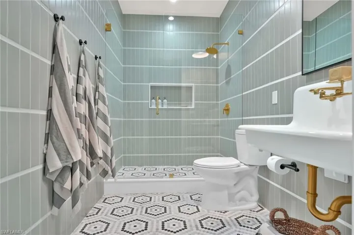 Cabana bath at this Marco Island luxury home with custom vintage-inspired design, wall paneling, designer wallpaper, and polished brass fixtures for guests by the pool.