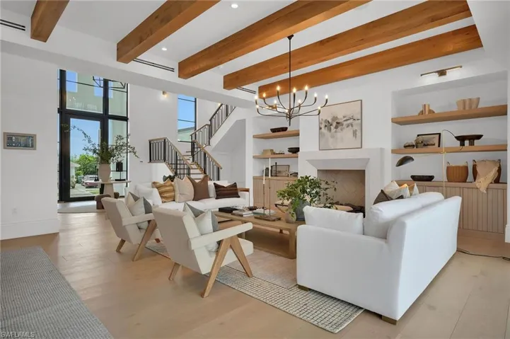 Living room featuring built in shelves, a fireplace, stairway, a chandelier, and light wood-type flooring
